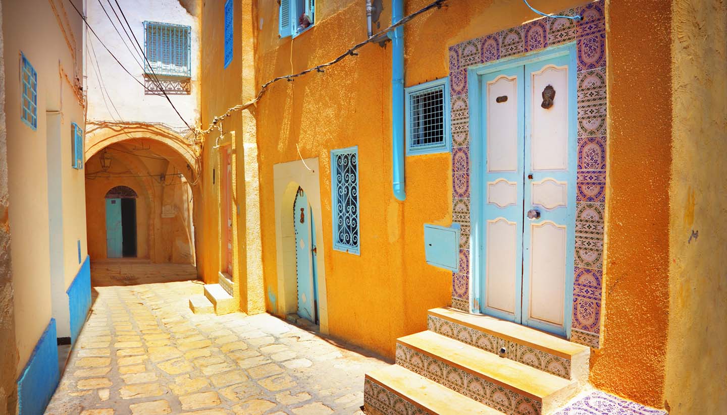 Tunesien - Arabian cobblestone street with orange colored building