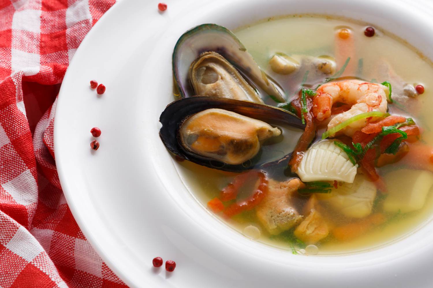 Meeresfrüchtesuppe mit Weißfisch, Garnelen und Miesmuscheln in einem mit Gewürzen garnierten Teller