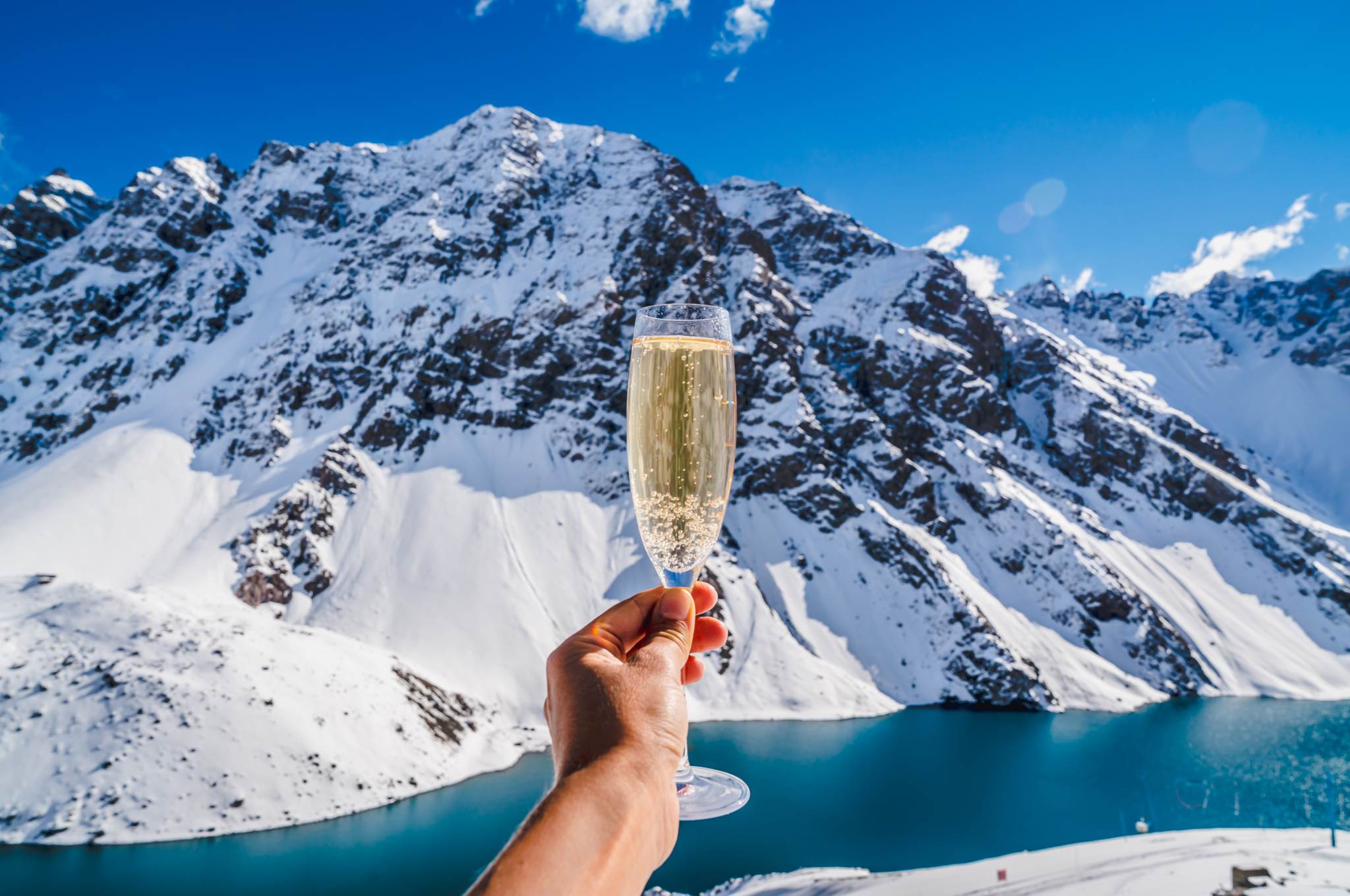 Die 10 besten Luxus-Skigebiete der Welt - Person, die ein Glas Champagner hält